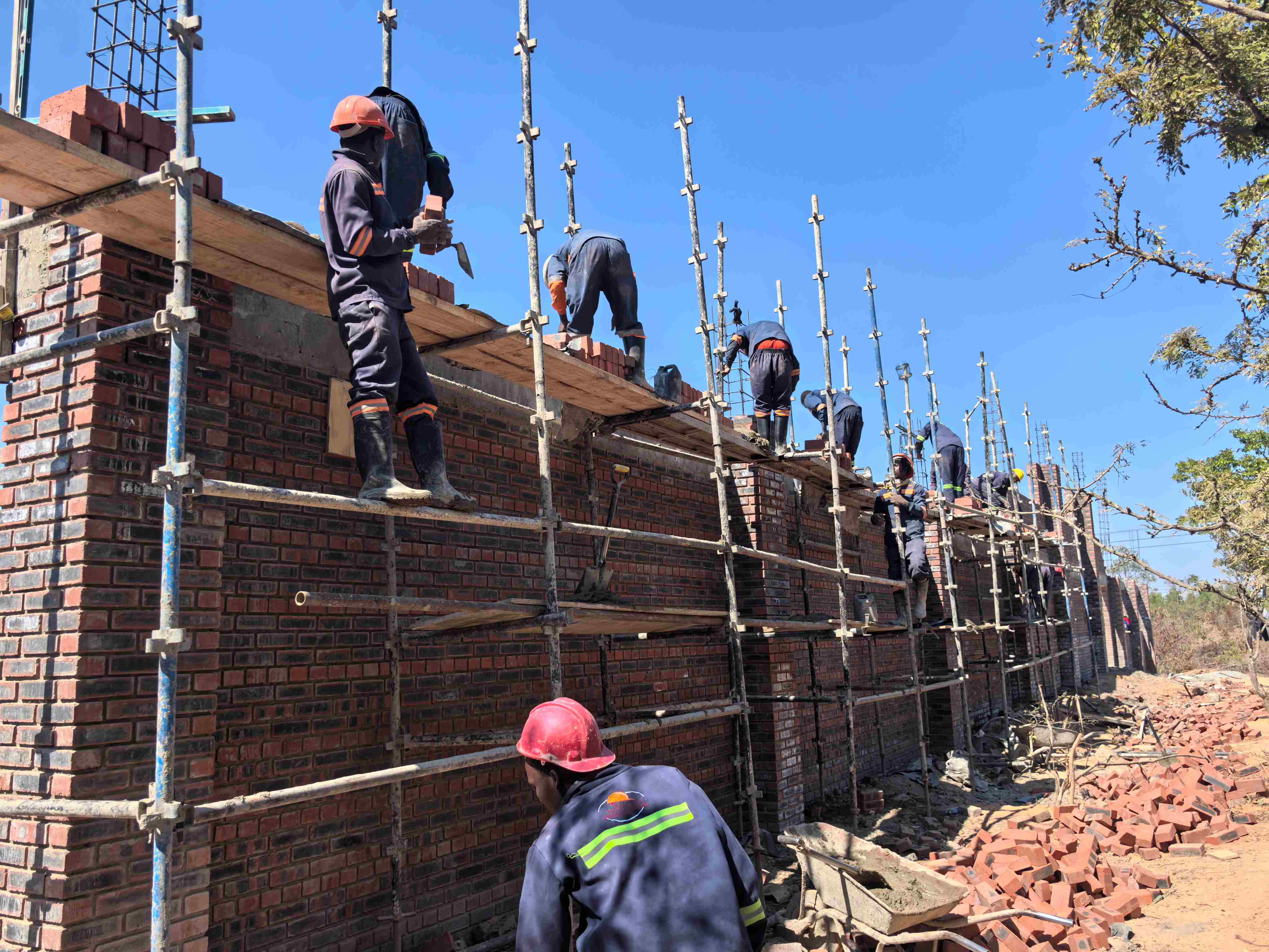 Masons building a brick boundary wall on scaffolding for Martcosy Construction